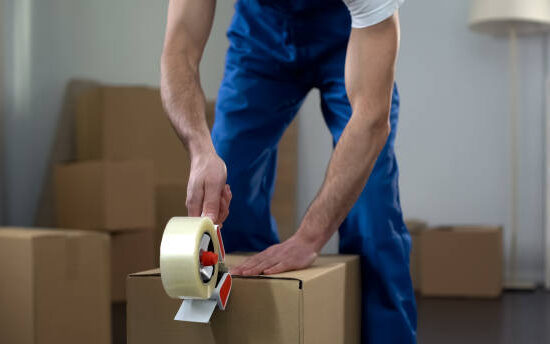 Moving company worker packing cardboard boxes, quality delivery services